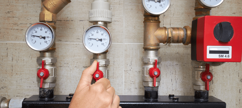 Photo of a person looking at the pressure guages and moving a valve to change the water presure.